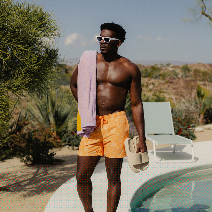 Stretch Swim 5.5" Bloom on man with towel over his shoulder carrying slides by the pool in a desert landscape