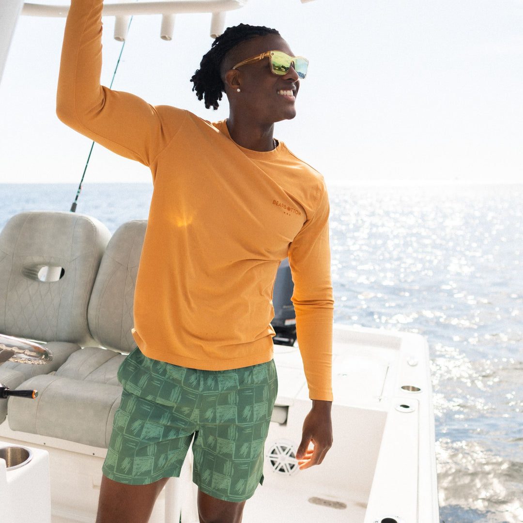 Stretch Swim 7" Everglades on man wearing Natural Dye Graphic Long Sleeve smiling on a boat in the ocean