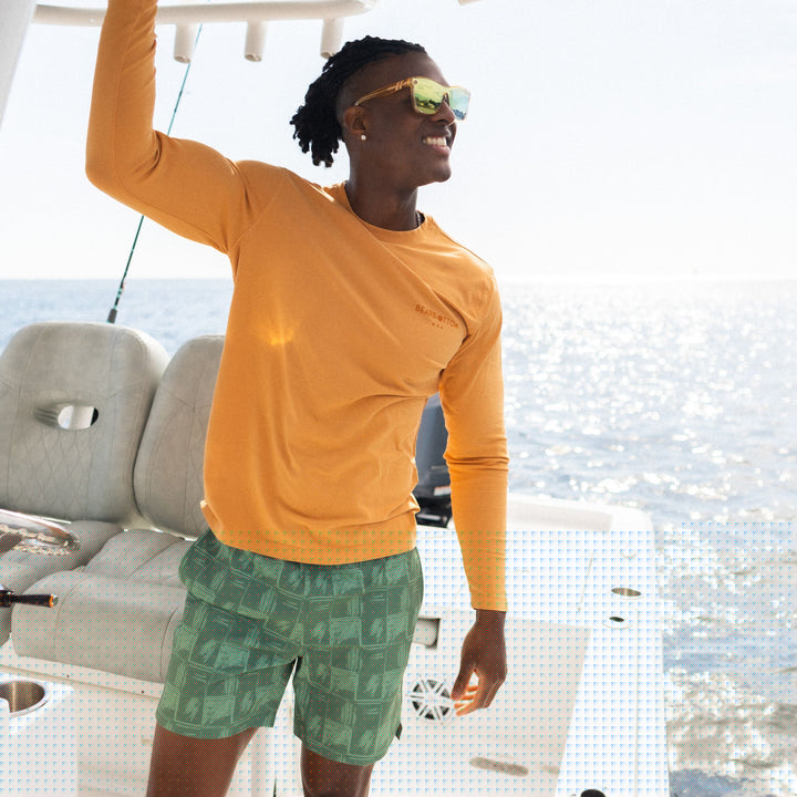 Stretch Swim 7" Everglades on man wearing Natural Dye Graphic Long Sleeve smiling on a boat in the ocean